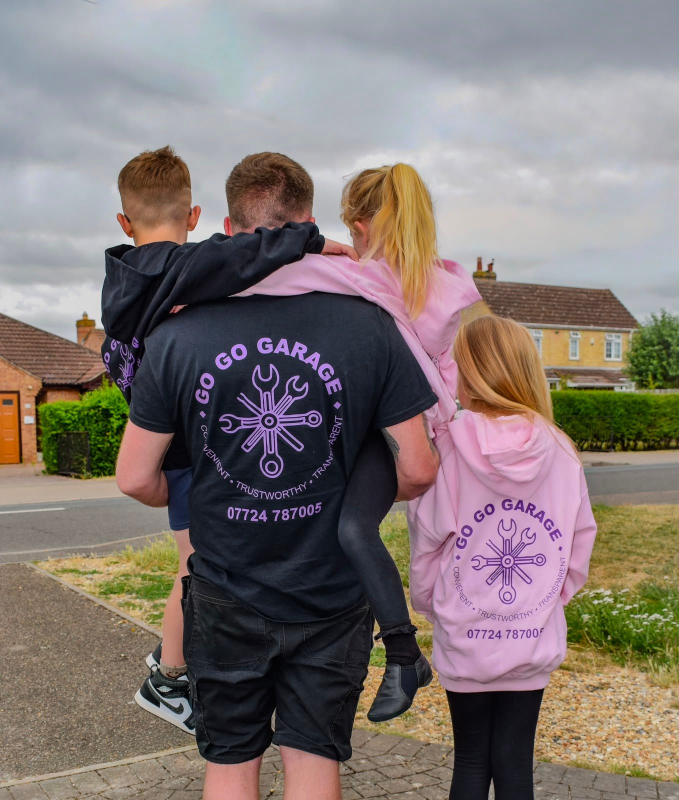 Tom Lee carrying his children, all wearing Go Go Garage branded hoodies