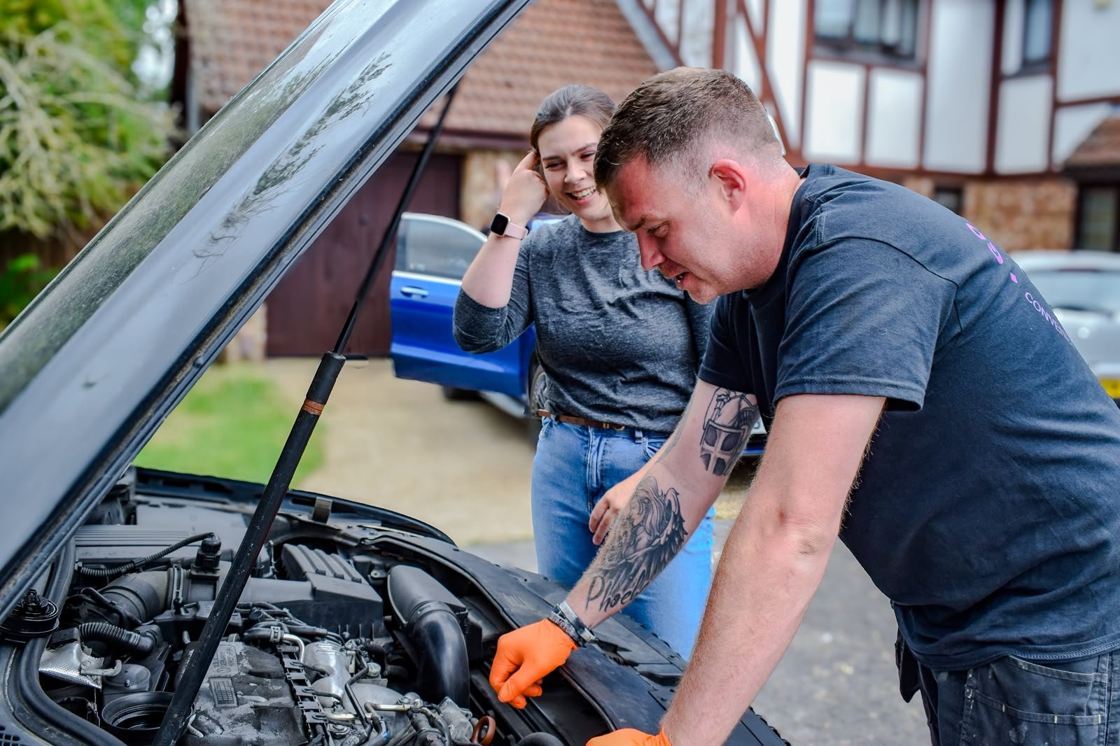Tom working on an engine at a customer's driveway while the customer watches